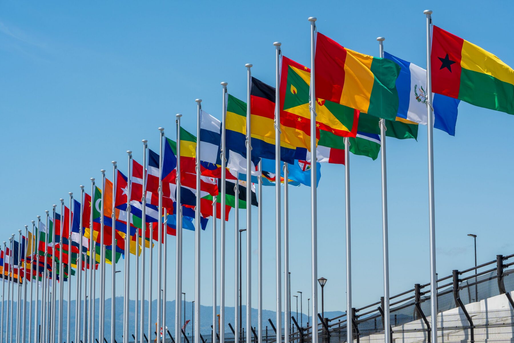 International Flags flying high against clear sky at the Yumeshima, an artificial island in Osaka Bay.