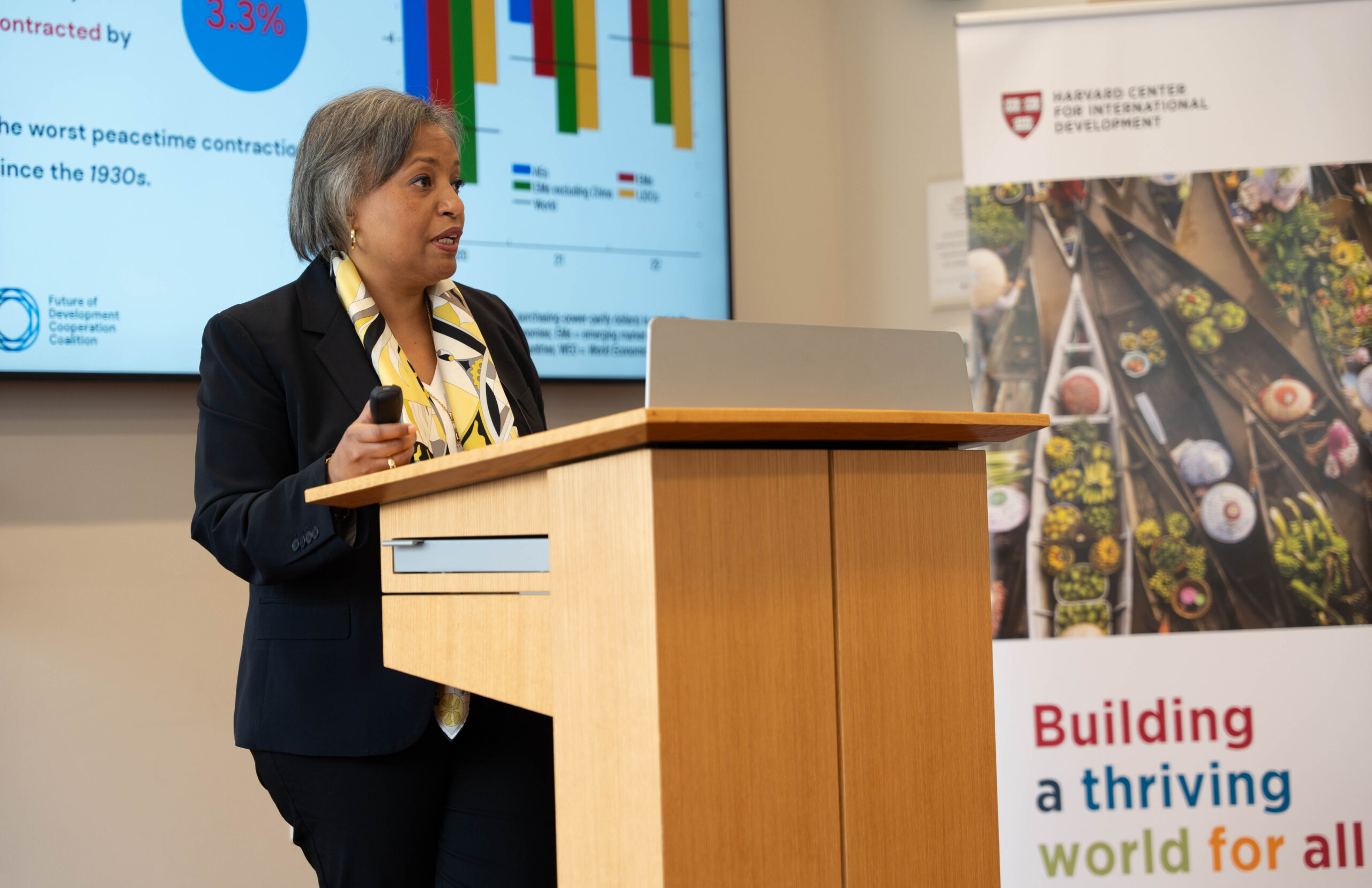 Image of Alexia Latortue speaking on a podium to the Harvard Center for International Development audience